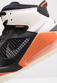 Černobílé vysoce kotníkové tenisky s detailem z mesh, oranžovými akcenty, strukturovaným koženým povrchem a viditelnou vzduchovou výplní ve podrážce.