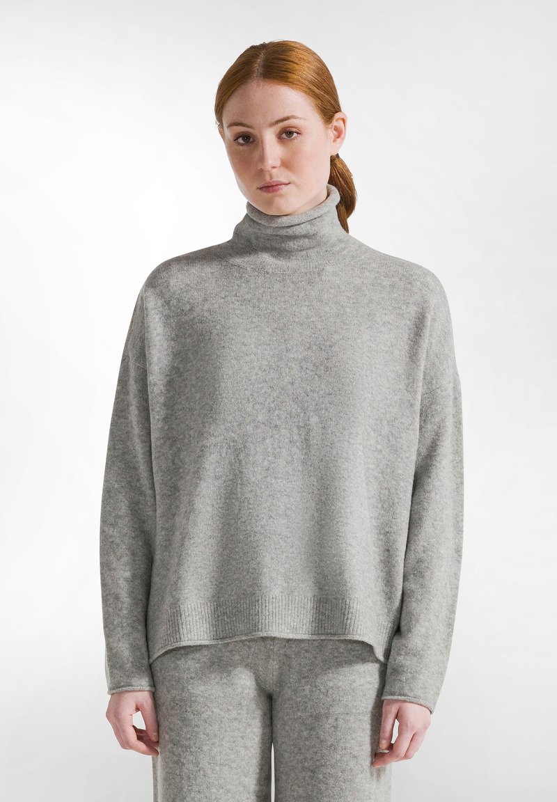 Hellgrauer Rollkragenpullover aus einem weichen, strukturierten Stoff mit legerer Passform. Verfügt über gerippte Bündchen und Saum, kombiniert mit passenden Hosen.