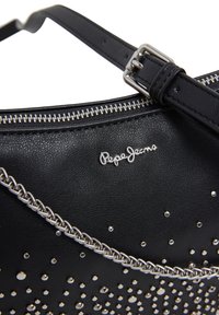 Czarna skórzana torba z srebrnymi ćwiekami i łańcuszkowym akcentem. Torba ma zamek błyskawiczny i widoczne logo. Gładka tekstura.