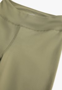 Leggings de sport en vert olive, fabriqués à partir d'un tissu extensible et lisse. Détails de couture le long de la taille et des jambes pour un maintien sécurisé.