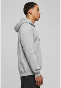 Grijze hoodie met een kangoeroe-pocket, ribgebreide mouwen en zoom. Gemaakt van zachte fleece, met een capuchon en trekkoord.
