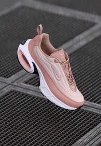 Baskets Nike Air Max 97 en maille rose doux et beige avec une semelle intermédiaire blanche, dotées d'une semelle extérieure noire, d'un bout arrondi et d'accents texturés.