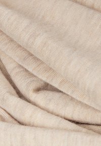 Zacht beige gebreide stof met een fijne geribbelde textuur en plooien die zachte krommingen en schaduwen vormen.