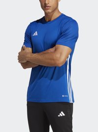 Kék sport póló rövid ujjal, fehér Adidas csíkokkal az oldalán és egy kis logóval a mellkason; sima textúra.