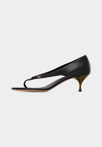Sandale à talon kitten en cuir noir avec fine bride sur les orteils et détail d'emblème doré sur le côté.