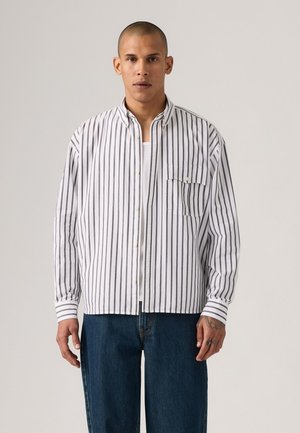 Camicia a righe bianca e blu navy, con maniche lunghe, taschino sul petto e colletto classico. Tessuto di cotone testurizzato.