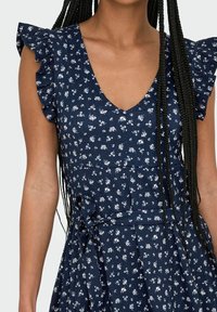 Navyblaues Kleid mit V-Ausschnitt, kurzen Rüschensäumen, Blumenmuster, gebundenem Taillendetail und strukturiertem Stoff. Enthält einen schwingenden Rock.