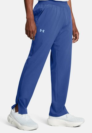 Blue athletic pants made of lightweight fabric, featuring a loose fit, side pockets, and zippers at the cuffs. Under Armour logo in light blue.