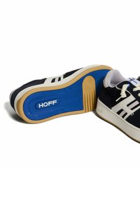 Sneaker nere con dettagli e lacci bianchi, dotate di una suola in gomma blu con un motivo testurizzato. Logo visibile sulla suola.