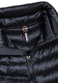 Chaqueta de plumas de color navy con una textura suave y brillante, que presenta costuras horizontales, un cuello alto y un cierre con cremallera. Logotipo de Colmar visible.