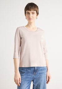 Lichtroze, lange mouwen top met een ronde halslijn. Zachte stof, slimfit ontwerp, gecombineerd met blauwe jeans voor een casual uitstraling.