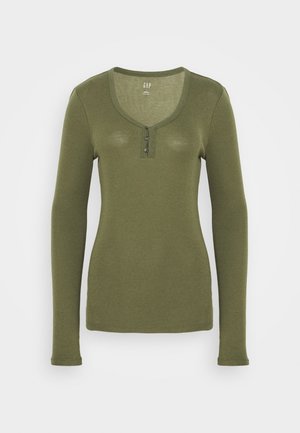 Oliivinvihreä, pitkähihainen, vartalonmyötäinen henley-paita, jossa on pyöreä pääntie ja kolme pientä nappia etunapissa.