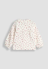 Weißes, langärmliges Babybluse mit rosa und roten Blumenmuster, gewelltem Kragen und gerafften Manschetten auf einem einfarbigen Hintergrund.