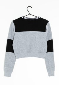 Sudadera recortada con cuerpo gris, paneles negros en los hombros y cuello a rayas en blanco y negro, con puños y dobladillo acanalados.