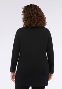 Tunic neagră cu mânecă lungă, având un croi lejer, decolteu rotund și detalii cu ținte pe manșete. Textură netedă, design până la șold.
