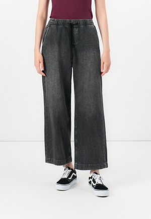 Wide-leg, dark gray denim pants with an elastic waistband and drawstring, paired with black and white sneakers. Smooth texture, casual style.
