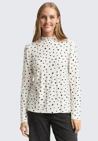 Weißes Langarmhemd mit schwarzen Punkten, ausgestattet mit einem gerafften, rüschenbesetzten Ausschnitt und einer glatten, weichen Stofftextur.