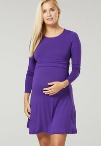 Purple maternity dress with long sleeves, round neckline, and a fitted bodice. Made from soft, stretchy fabric, falling above the knee.