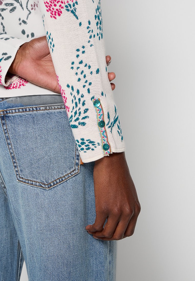Gebreide trui met bloemmotief in roze, teal en groen; heeft decoratieve knopen op de mouwen en een zachte, gestructureerde afwerking.