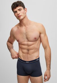Bóxer azul oscuro con una cintura elástica de marca. La tela parece suave y elástica, ajustándose cómodamente alrededor de la cintura y los muslos.