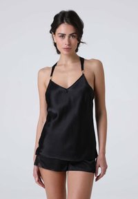Camisola nera in satin con sottili spalline e accenti dorati, caratterizzata da un neckline a V e un bordo in pizzo, abbinata a pantaloni corti coordinati.