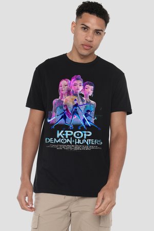 Junger Mann trägt ein schwarzes T-Shirt mit bunten animierten Figuren, die leuchtende Waffen halten, und dem Schriftzug "K-Pop Demon Hunters" auf der Vorderseite.
