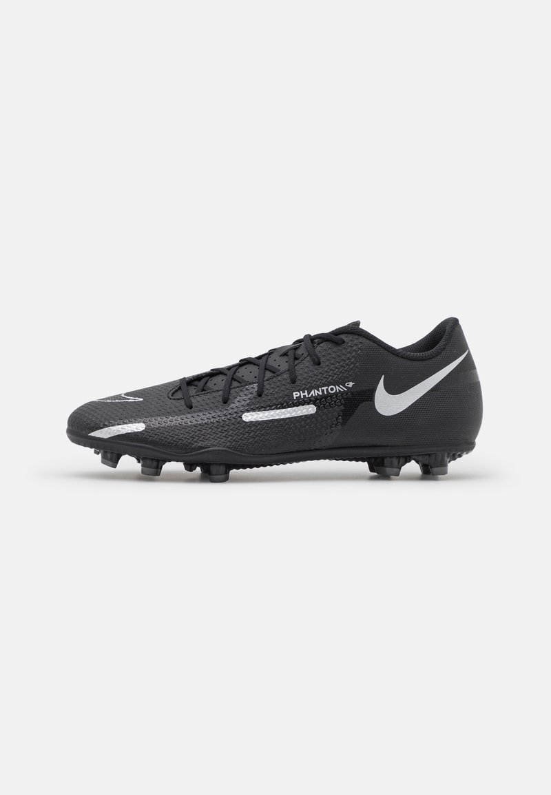 Bota de fútbol Nike Phantom negra con logo swoosh blanco, cordones y tacos sobre un fondo blanco liso, vista lateral.