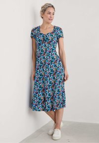 Floral maxi dress with short sleeves, featuring a purple, blue, and brown pattern. Made of soft fabric, it has a square neckline and a flowing silhouette.