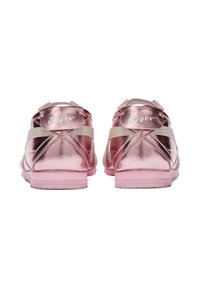 Sneakers metallici rosa con una finitura liscia, dotati di fasce incrociate e una suola in gomma. Marchio visibile nell'area del tallone.
