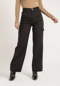 Pantalons cargo noirs taille haute avec poches latérales, fabriqués dans un tissu doux. Dotés d'une fermeture à bouton doré et d'un design à jambes larges.