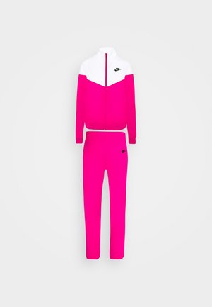 Pink og hvid Nike-træningsdragt med en jakke med lynlås og matchende bukser, begge med sorte Nike-logoer på brystet og låret.