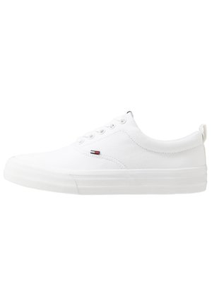 Baskets basses blanches avec lacets sur l'avant, semelle épaisse et petit logo rouge, blanc et bleu sur le côté, vues de l'extérieur.