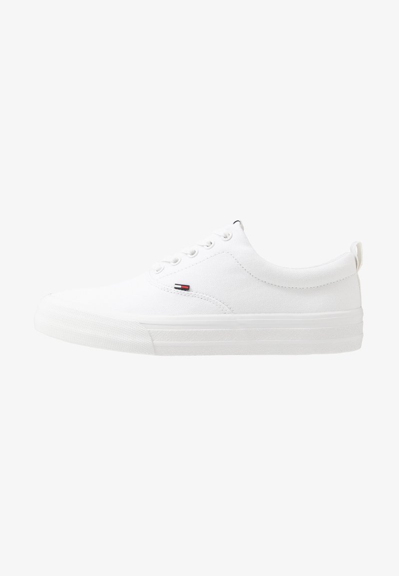 Baskets basses blanches avec lacets sur l'avant, semelle épaisse et petit logo rouge, blanc et bleu sur le côté, vues de l'extérieur.