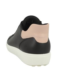 Sneaker in pelle nera con un accento rosa chiaro sul tallone, suola bianca, texture liscia e design minimalista. Presenta cuciture sul tallone.
