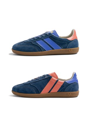Deux baskets en daim avec des semelles marron, l'une avec des bandes bleues et un talon, l'autre avec des bandes corail et un talon bleu, toutes deux avec des lacets.