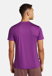 Paarse T-shirt met korte mouwen van lichtgewicht stof. Heeft een ronde hals en een gladde textuur. Etiket zichtbaar aan de linkerkant.
