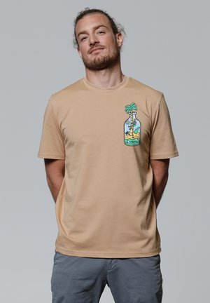 Beige T-shirt met korte mouwen van zachte stof, voorzien van een kleurrafische afbeelding van een palmboom in een fles op de linkerborst.