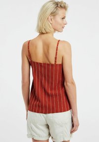 Top a canottiera color ruggine con spalline sottili, caratterizzato da righe verticali e un tessuto testurizzato. La vista posteriore mostra un orlo dritto.