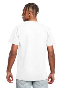 Hvid bomulds t-shirt vist fra bagsiden, med korte ærmer og en lige sømlinje, med en glat tekstur og ingen grafik.