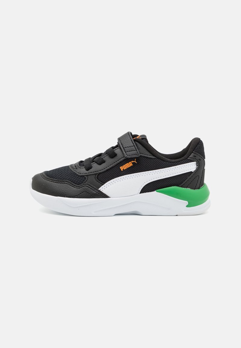 Baskets Puma en noir et blanc avec détail vert au talon, logo orange, dessus en mesh et cuir, bride à scratch, et semelle en caoutchouc blanche, vue de côté.