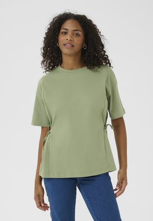 Haut vert clair à manches courtes avec un col rond et des liens latéraux ajustables. Fabriqué en tissu doux, il a une coupe décontractée et une texture lisse.