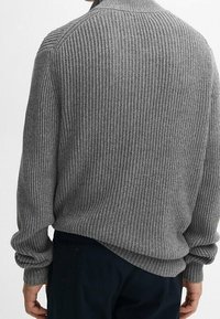Maglione grigio a maglia con coste verticali, colletto alto e maniche lunghe. Vestibilità rilassata con una forma leggermente oversize e polsini a sbuffo.