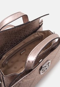 Kovová kabelka v barvě růžového zlata s monogramovým vzorem, vybavená dvěma horními držadly, vnitřní kapsou na zip a dekorativním kovovým doplňkem.