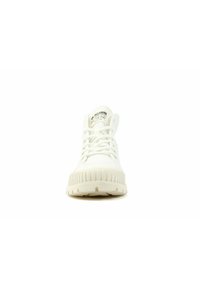 Baskets blanches avec une semelle en caoutchouc texturé, bout rond et lacets plats. Présente une étiquette logo sur la languette. Design épuré et minimaliste.