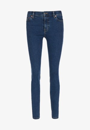 Tmavě modré úzké džíny z denimu, s páskem se středním pasem, pěti kapsami a detaily z měděného kovu.