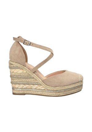 Beige suede wedge sandals with a rounded toe, crisscross ankle strap, and woven jute-covered platform with metallic accents.
