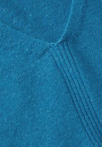 Kankaan teal neulontamateriaali, jossa on pehmeä rakenne, tasainen kuvio ja hillitty kiilto, esittelee ainutlaatuista uritettua yksityiskohtaa.