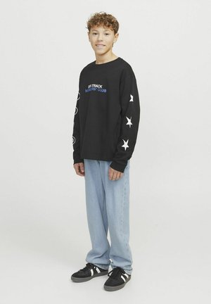 Maglietta nera a maniche lunghe con la scritta "OFF-TRACK MEMBERS' CLUB", con motivi a stella bianchi sulle maniche, abbinata a jeans blu chiaro e sneaker nere.