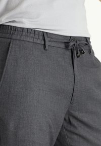 Grijze geweven broek met een elastische tailleband en een verstelbare koord. Voorzien van twee zakken en een subtiele textuur voor een casual uitstraling.