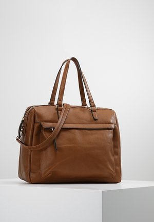 Sac à main en cuir marron avec double poignée et poche zippée à l'avant, présenté sur une surface blanche devant un fond gris clair.